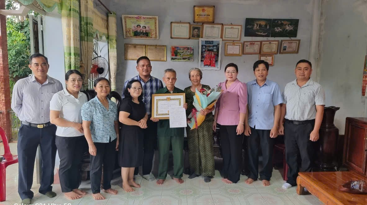 'A group of people in traditional attire is gathered around a table, each receiving a certificate and standing in a room with framed pictures on the wall.

AI-generated content may be incorrect.'