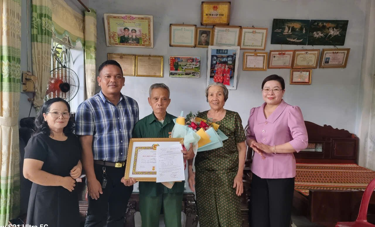 'The image shows a group of people standing in a room with decorations, a certificate, and various decorations on the wall.

AI-generated content may be incorrect.'